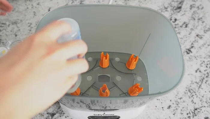 Place the lower basket on the base, add bottles and pump parts, then add the upper basket (if using) and lid. Leave space around items for steam circulation.