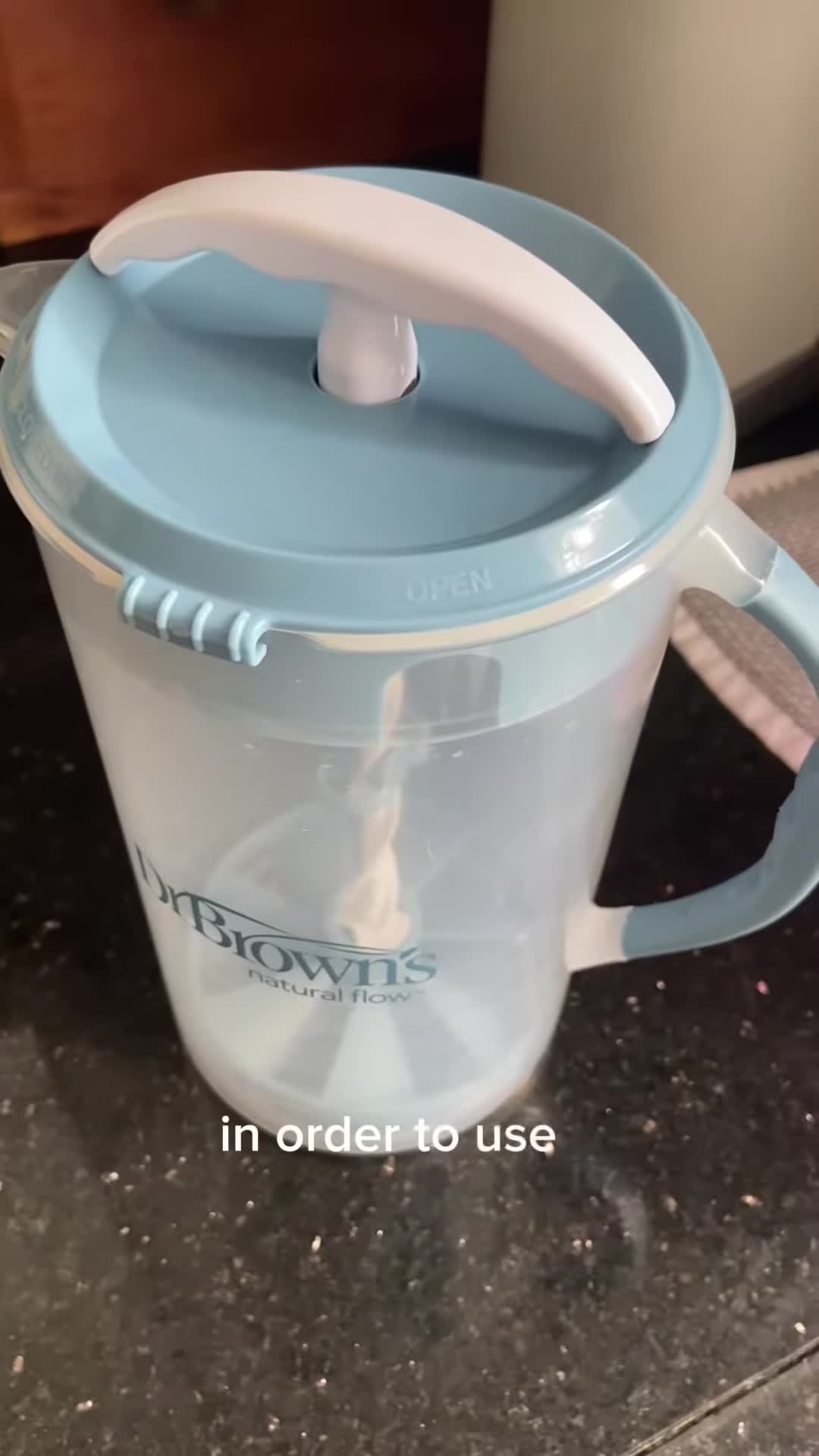 Demonstrating how to open the Dr. Brown's Formula Mixer by pushing the tab.