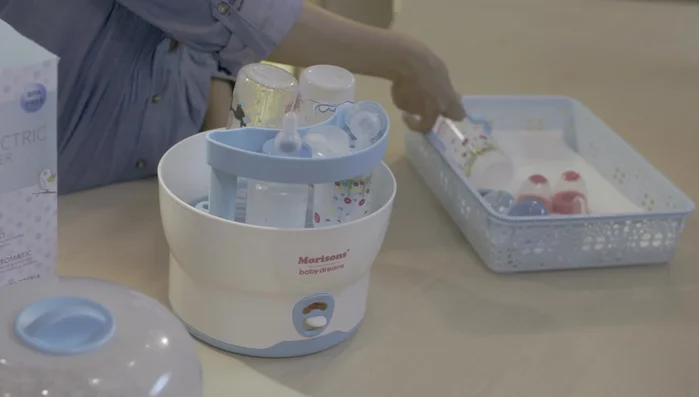 Use the tongs to remove the sterilized bottles.