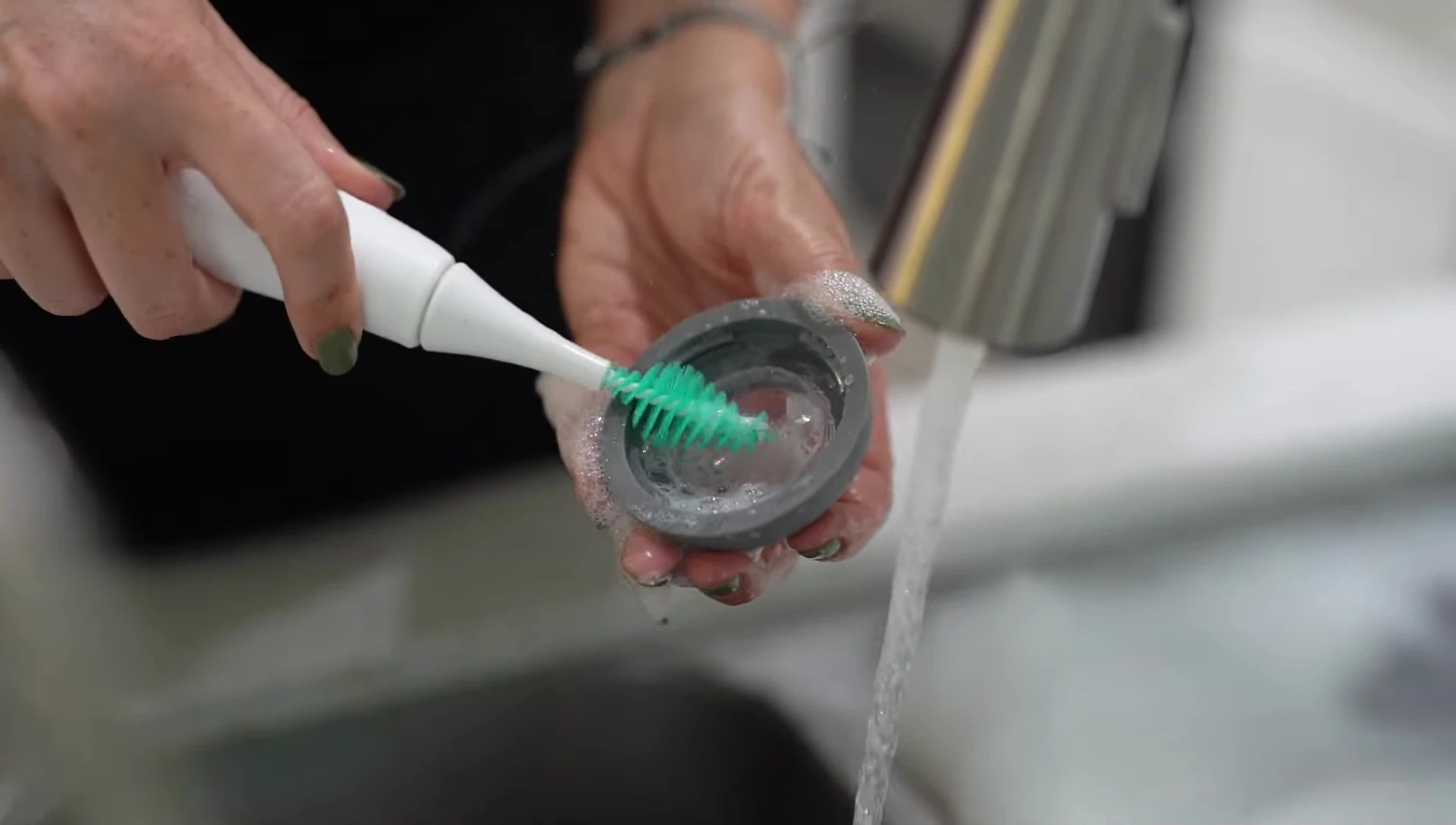 Demonstration of the small brush head effectively cleaning a bottle nipple.